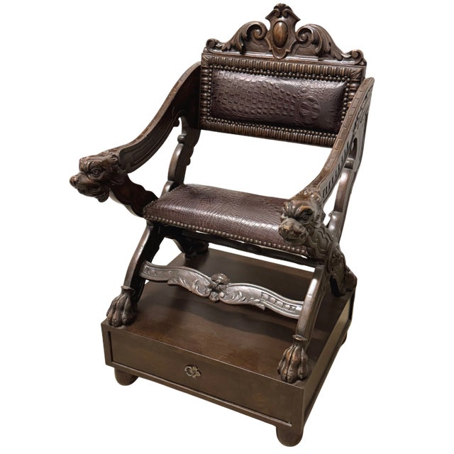Renaissance Revival–style Savonarola chair with carved dog-head arm terminals, scrolled cresting, and paw feet. The X-form...