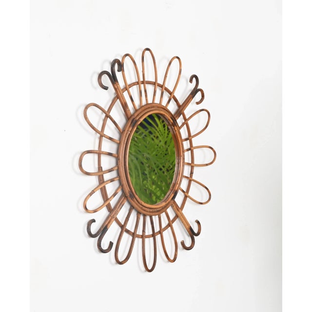 Wonderful Mid-Century French Riviera style sunburst mirror entirely made in curved rattan. This stunning organic mirror...