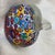 This is a colorful Murano Millefiori apple paperweight featuring multicolored glass mosaic murrini and a clear applied stem.