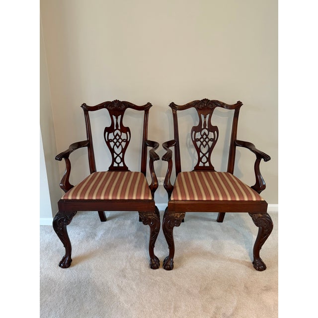 This traditional pair of mahogany arm chairs features a Chippendale style with hand carved backs and cabriole legs ending...