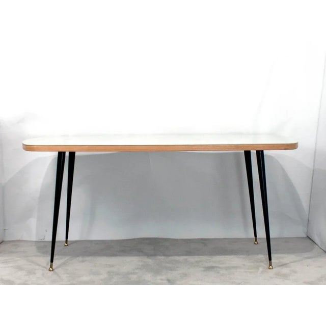This dining table is made of DM with a white glass top. The iron legs are lacquered in black with golden brass leg...