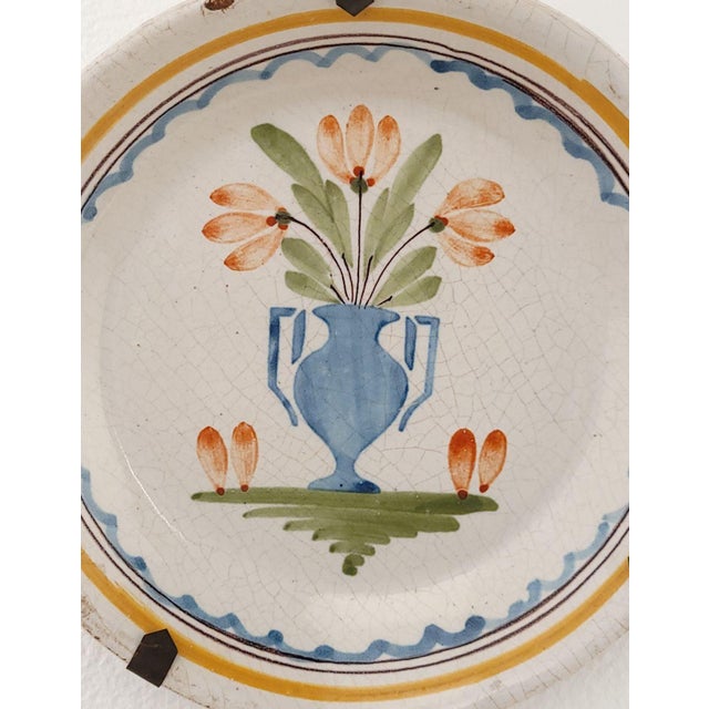 A French faïence plate with a vase and flowers, 18th/19th century.