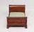 The diminutive mahogany sleigh bed with green and white upholstery. The piece is from the late 20th century.