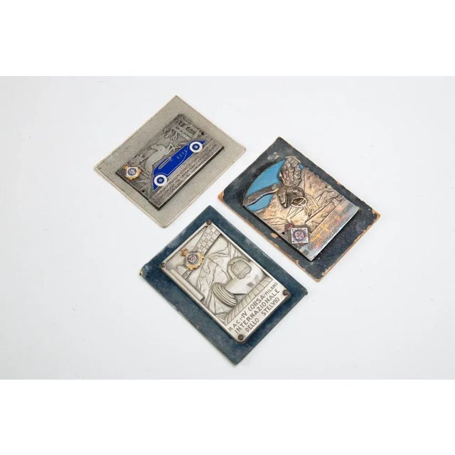Group of three silver-plated metal raci plaques with polychrome enamels. Raci iv stelvio international race - first bormio...