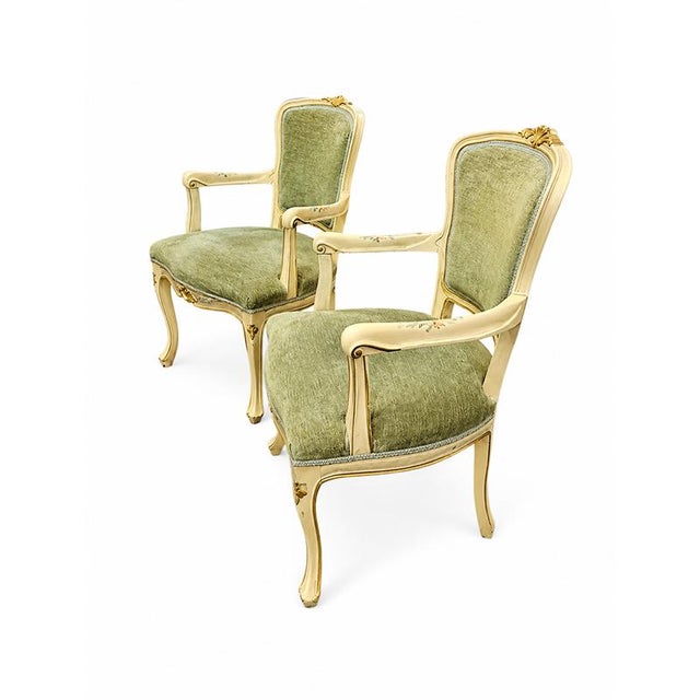 An elegant pair of lacquered and gilded wooden armchairs, crafted in the first half of the 20th century in the refined...