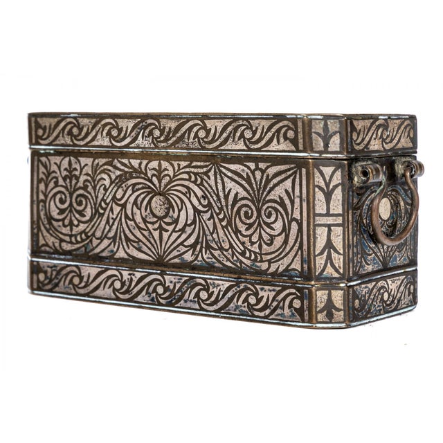 An antique silvered bronze betel nut box with a rectangular body, hinged lid, three sectioned interior chambers covered...
