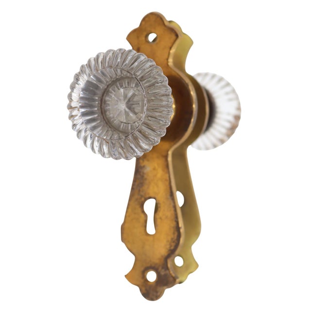 Vintage passage door knob set with round fluted clear glass door knobs paired with stamped brass back plates. The original...