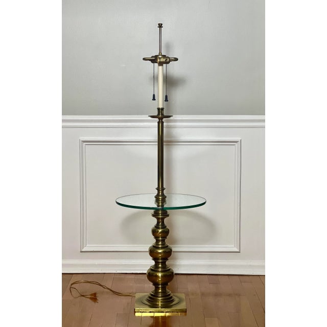 Fabulous vintage brass floor lamp with glass table by Stiffel, circa 1970's. The lamp features two lights with pull chains...