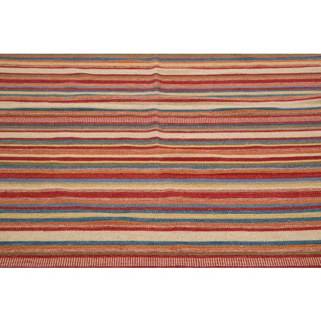 Beautiful Modern Kilim hand-knotted wool rug with a multicolor accents in an all-over geometric stripe design. This rug...