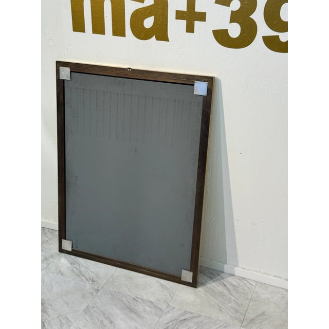 A sleek rectangular wall mirror with a bold stepped brass frame, showcasing clean lines and refined craftsmanship. The...
