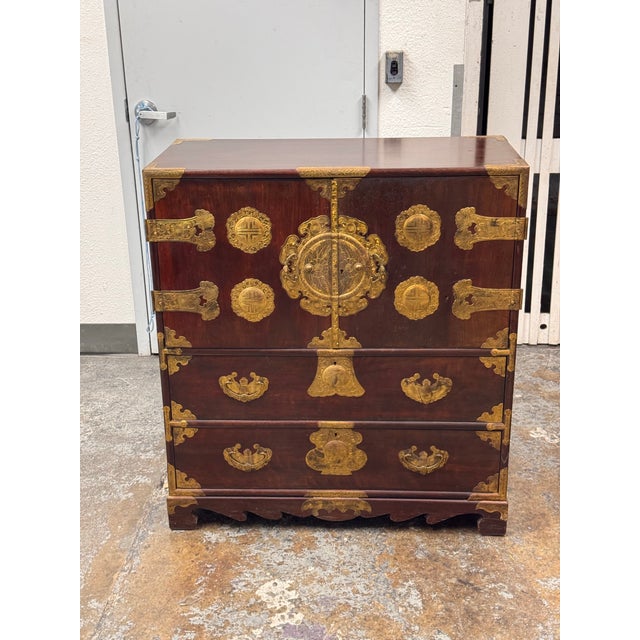 Design Plus Gallery presents a Japanese Gilt-Mounted Tansu Chest by Lord Co. This vintage chest has a reddish-brown wood...