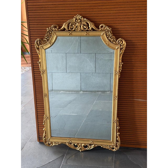 An elegant French Louis XV style giltwood wall mirror, beautifully hand carved and retaining its original beveled mirror...