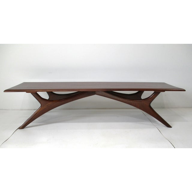 A solid walnut Mid Century sculptural coffee table with splayed legs in the manner of Vladimir Kagan. This very well...