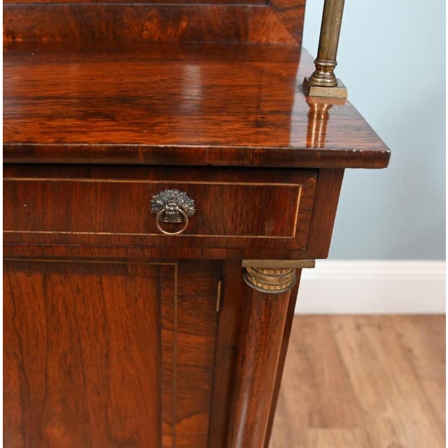 A Regency period mahogany chiffonier of fine quality with ormolu mounts Classic lions head handles to the front of the...