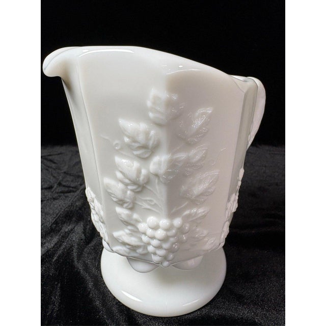 This Westmoreland milk glass pitcher features the classic Paneled Grape pattern, showcasing detailed embossed grape...