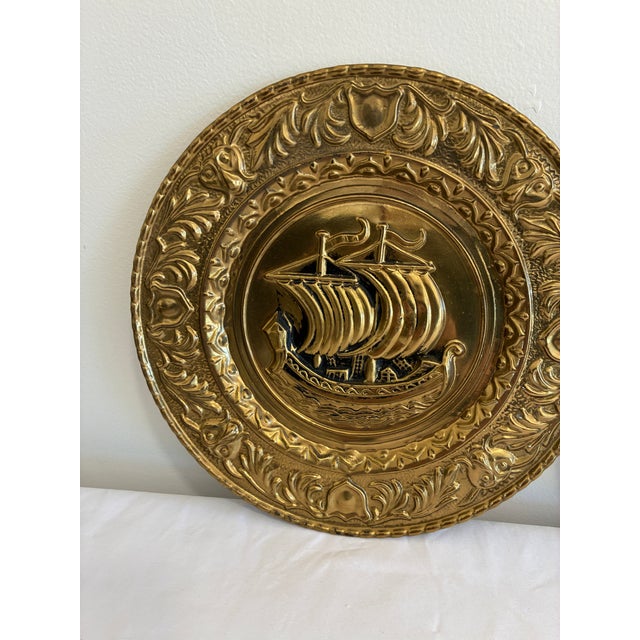 A handsome pair of vintage English brass plates with raised sailing ships at their centers, one a two-masted vessel and...