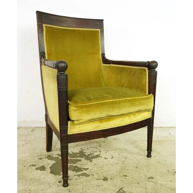 Antique French style arm chair with yellow velvet upholstery and a carved dark wood tone frame. Good condition with some...
