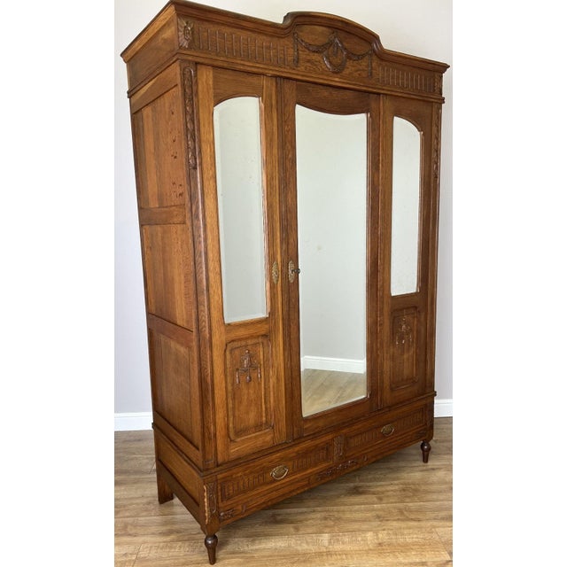 A stunning Antique French wardrobe crafted in oak with elegant mirrored doors and beautifully carved decorative detailing...
