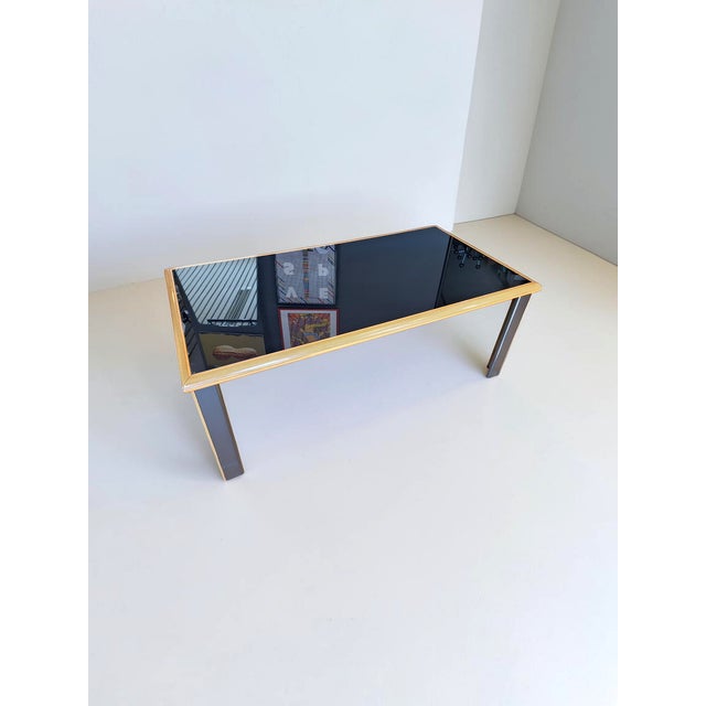 Dining table made of black painted glass and black lacquered wood and maple. The table was designed by Pierre Cardin for...