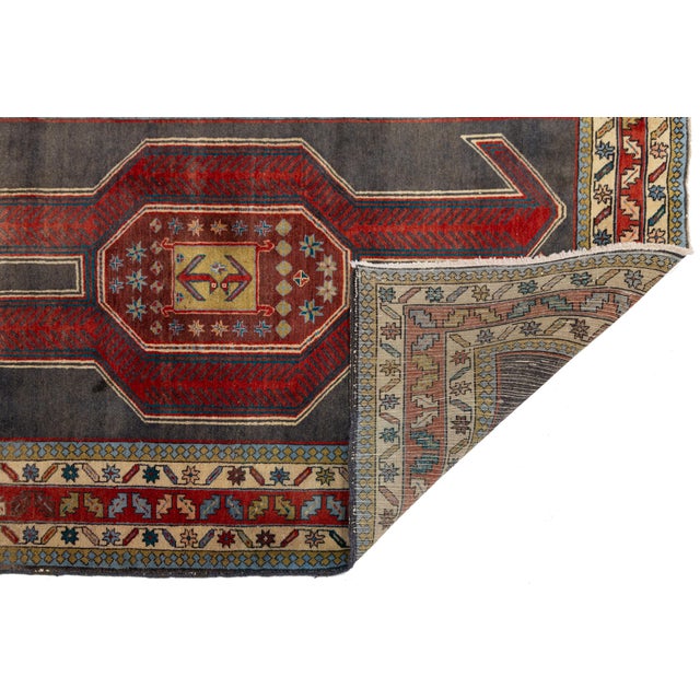 An exceptional vintage Caucasian Kazak wool runner featuring a striking graphic composition set against a deep charcoal-...