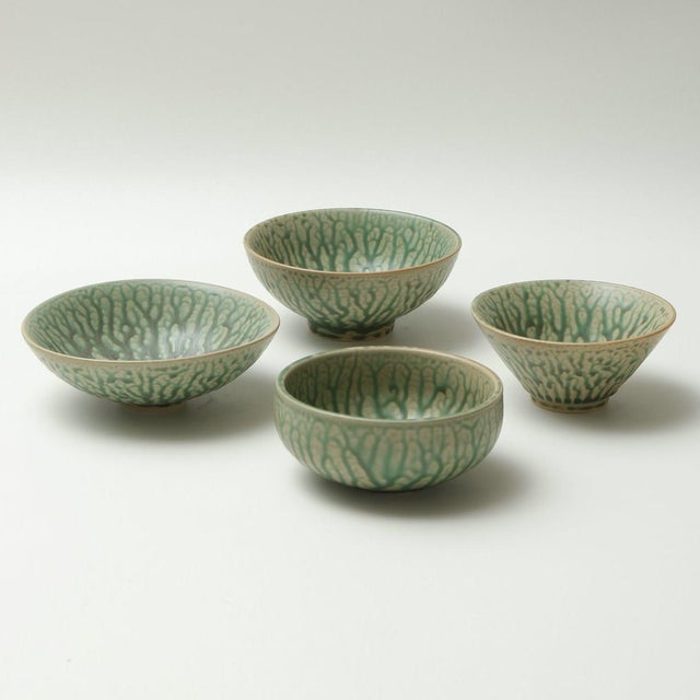 A set of four Japanese-style ceramic bowls, each varying in shape and size; the glaze features a vein-like pattern, with a...