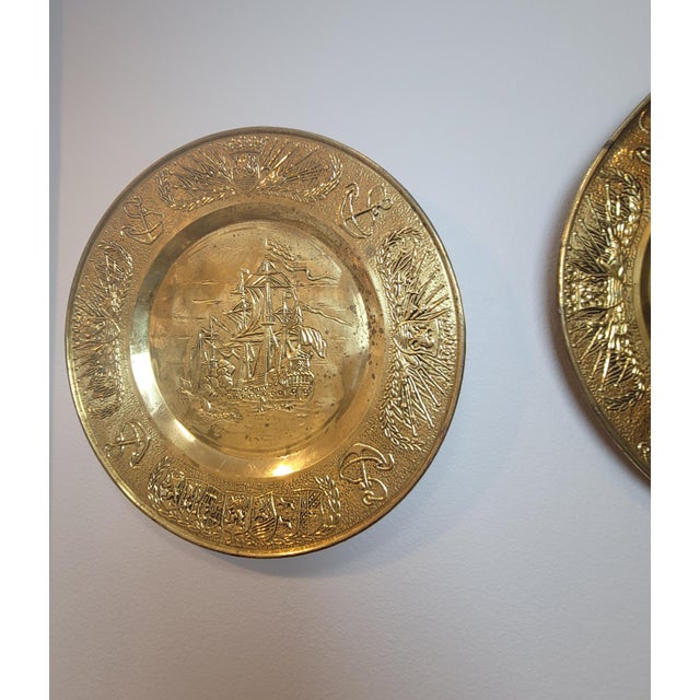A striking pair of oversized 17.25-inch English repoussé brass wall plaques, perfect for adding a nautical or British...