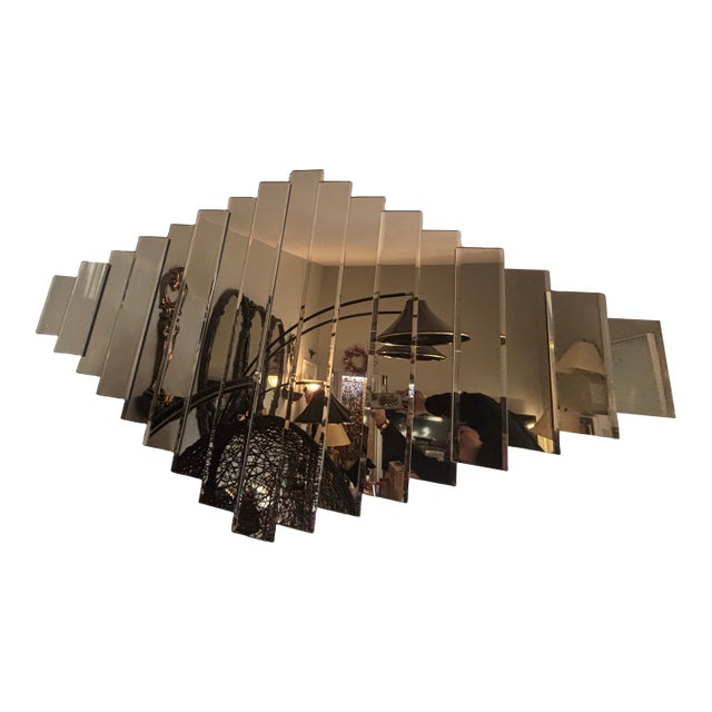 It’s a wall-mounted geometric mirror composed of several rectangular panels, each beveled and slightly angled. The pieces...