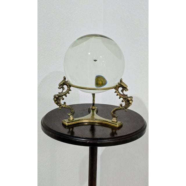 Elevate your decor with this unique glass crystal ball mounted on an ornate brass stand featuring detailed dragon motifs....