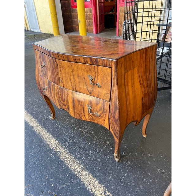 This striking 20th-century Italian bombé commode beautifully showcases the dramatic elegance of the Louis XV Rococo...