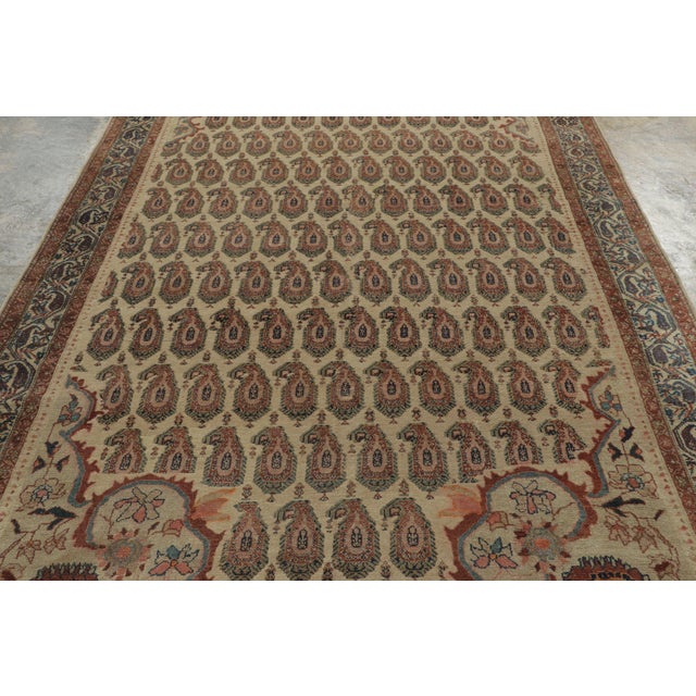 Handwoven in wool, circa 1900–1920, this antique 7x12 Malayer rug features an elegant all-over paisley design in ivory,...