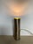 Vintage mid-century modern accent lamp in brushed metal, featuring a sleek, minimalist tubular cylinder housing on a small...