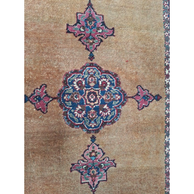 Vintage handwoven runner rug featuring a warm camel-colored field and a series of medallion in rich tones of deep red,...