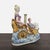 This Capodimonte sculpture features a graceful lady seated in a decorated chariot, accompanied by a cherub and a swan....