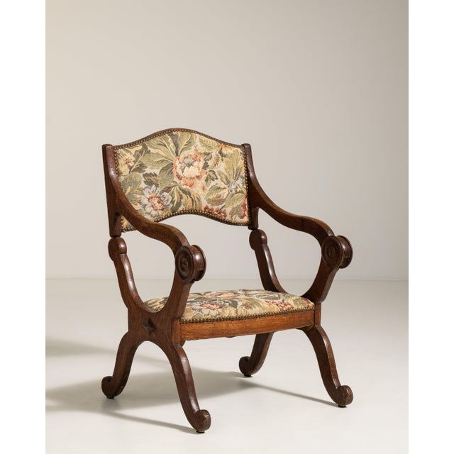 A traditional oak armchair featuring tapestry upholstery, reflecting the decorative arts tradition of integrating textile...
