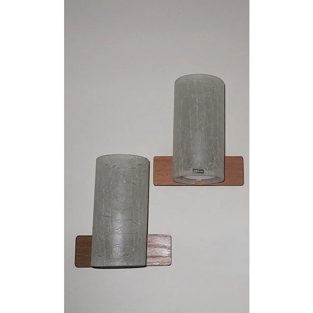 Pair of Doria cylindrical wall lights in frosted crackled glass on teak frames, 1960s. Doria label on front, Doria labels...