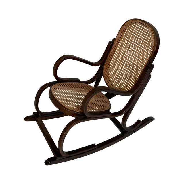 Antique rocking chair in children’s size. Made from bent wood (oak) and a wicker seat and back rest. Made in the style of...