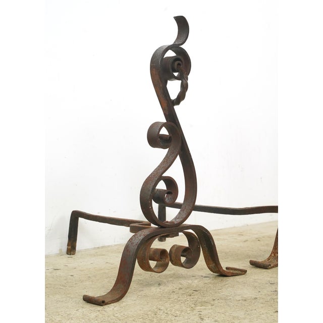 Antique Arts & Crafts style andirons made of wrought iron with a loose ring on the top attached to a curled design....