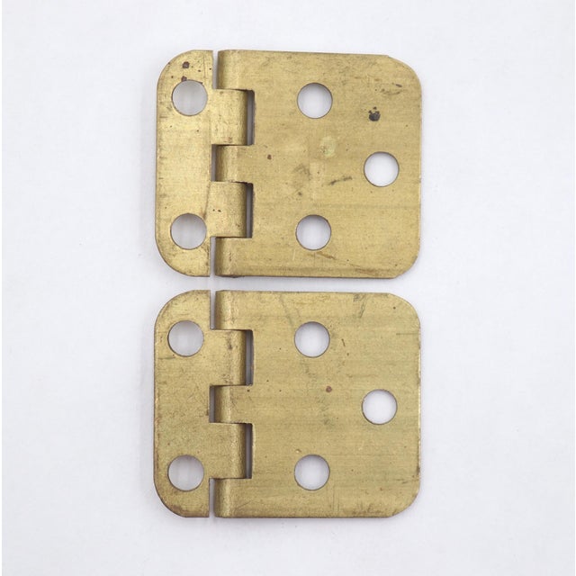 Vintage face mount cabinet door hinges made of brushed brass with flat tips, five knuckles, and a template hole pattern....