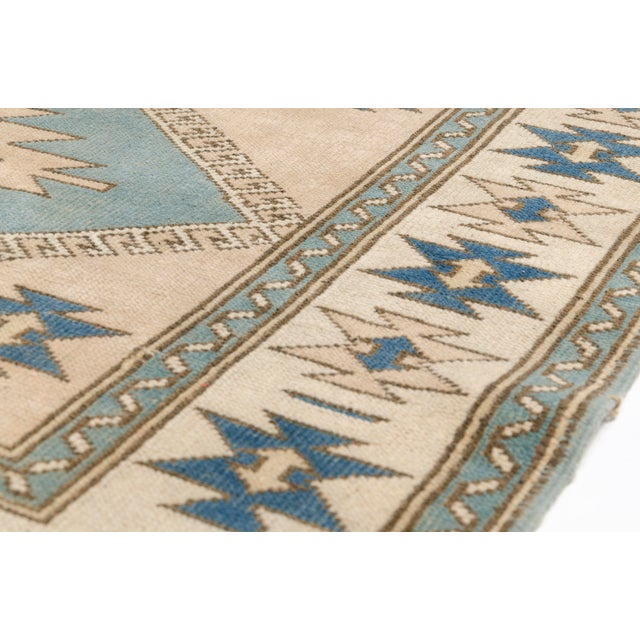 This is a vintage Turkish Oushak rug from the Mid 20th Century. The piece was hand-knotted.