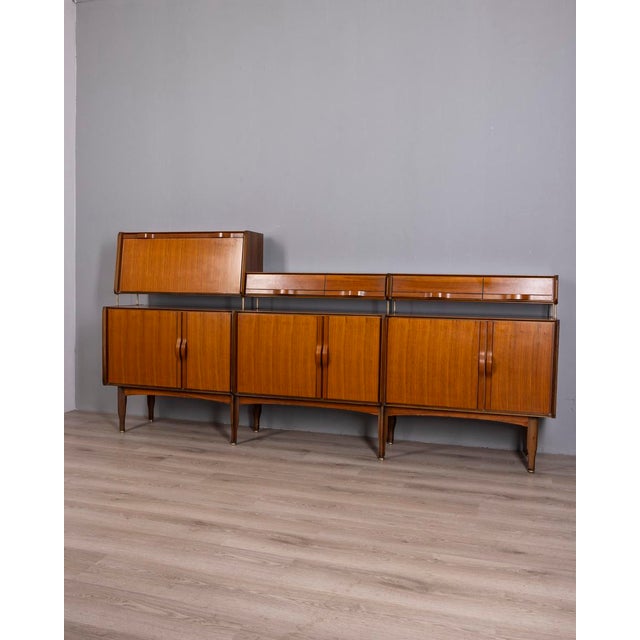 Large teak sideboard with gilded brass accents, three hinged doors at the bottom, drawers and a drop-leaf door at the top....