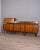 Large teak sideboard with gilded brass accents, three hinged doors at the bottom, drawers and a drop-leaf door at the top....