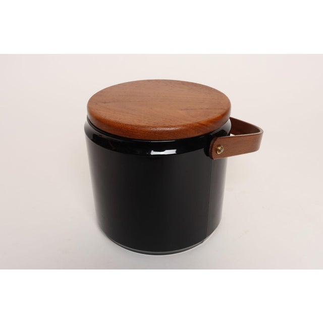 Stylish ice bucket in black patent vinyl with solid teakwood lid and sculptural handle and off-white plastic insulated...