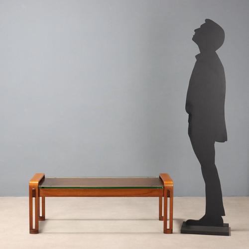 Coffee table with wooden frame and rectangular glass top. This piece is attributed to the mentioned designer/maker. It has...