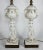 Pair of 20th century parcel-gilt porcelain table lamps taking the form of seated cherubs. Pierced brass bases. Unsigned....