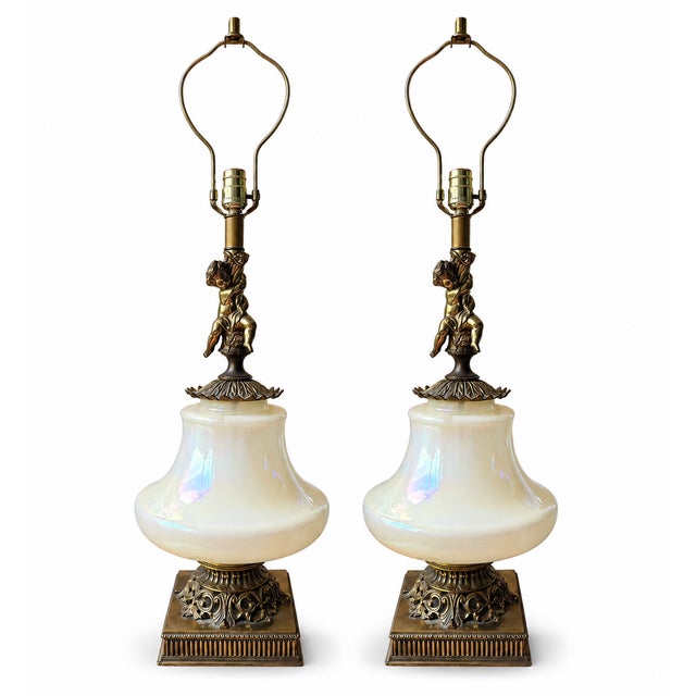 A striking and rare pair of mid-century Hollywood Regency table lamps crafted with oversized opaline glass urn fonts...