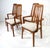 A set of four teak wood framed dining chairs two with arms and two sides all with upholstered seats in a tight woven...