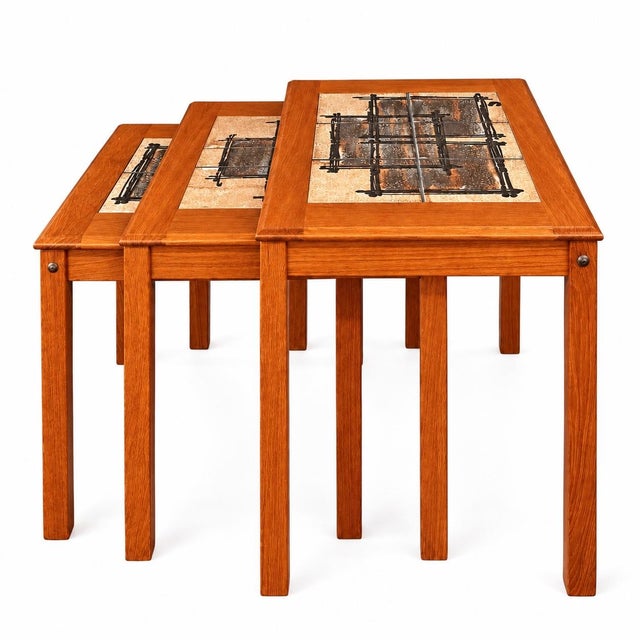 A handsome set of three vintage nesting tables crafted by Trioh Møbelfabrik featuring warm-toned teak frames and inset...