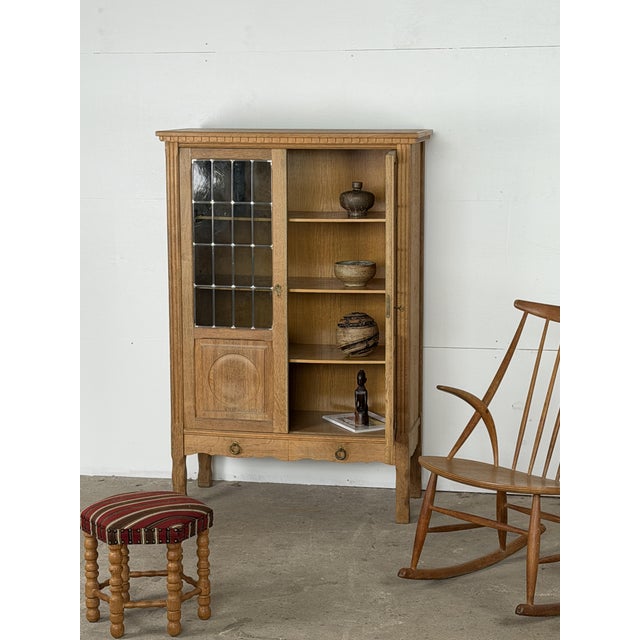 Danish display cabinet in solid oak with leaded glass doors, 1960s. The upper section is enclosed by two glazed doors,...