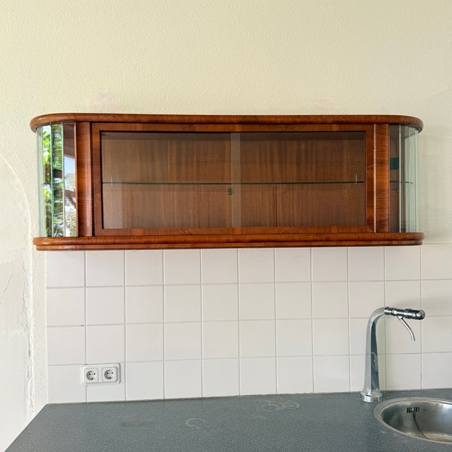Exuding mid-century elegance, this is a Polish wall-mounted showcase cabinet dating from the early 1960s. It features...