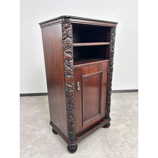 Art nouveau cabinet with a shelf, decorated with distinctive floral carvings. Professionally stained and repolished. The...